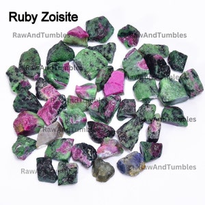 Peut inclure: Une collection de petites pierres de zoïsite rubis brutes, vertes et roses. Les pierres sont roulées et ont un aspect naturel et brut.
