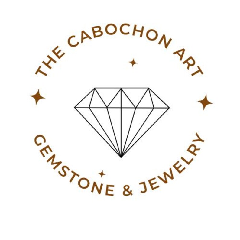 Puede incluir: Un logotipo para "The Cabochon Art Gemstone & Jewelry" presenta una ilustraci&oacute;n de diamante en el centro, rodeada de texto en un arreglo circular. El texto y el diamante son negros y marrones sobre un fondo blanco.