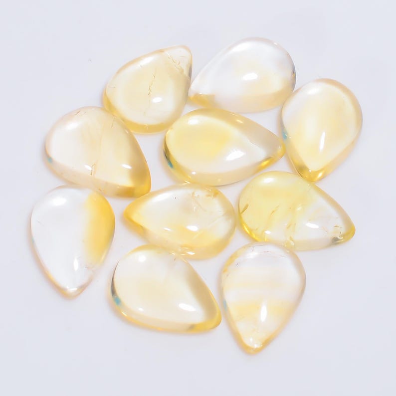 May include: A collection of 10 teardrop-shaped, translucent yellow gemstones. The stones are smooth and polished, with a slight shimmer.