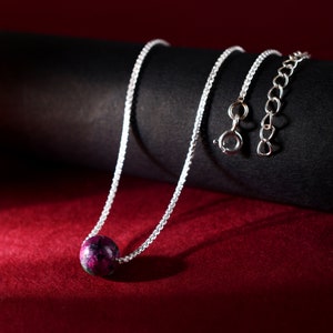 Puede incluir: Un collar de cadena de plata con un solo colgante redondo de piedra preciosa rosa y verde.