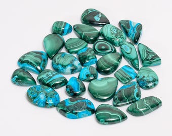 May include: A collection of polished malachite gemstones in various shapes and sizes. The stones display a mix of deep green and vibrant turquoise blue colors, with unique swirling patterns. The gemstones are arranged on a white surface.