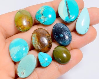 May include: A collection of polished gemstones in various shapes and colors, including turquoise, brown, and green. The stones are oval, teardrop, and irregular shapes. The turquoise stones have visible veining.