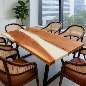 May include: A rectangular wooden dining table with a light-colored epoxy resin center. The table is supported by black metal legs and surrounded by six chairs with woven backs and brown leather seats. The table measures approximately 72 inches long.