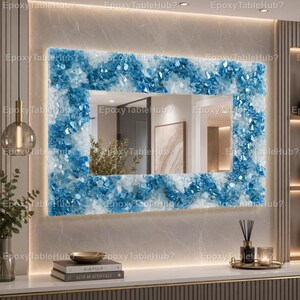 May include: A rectangular wall mirror featuring a thick, textured frame composed of numerous small, jagged blue and white crystalline pieces. The mirror is mounted on a light-colored wall and reflects a room interior with a framed wall art piece.
