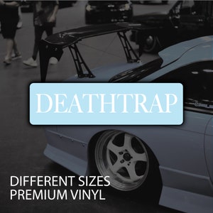 Peut inclure: Une voiture bleue avec un grand aileron noir et un autocollant blanc qui dit "DEATHTRAP". La voiture a une grande roue argentée et le texte "DIFFERENT SIZES PREMIUM VINYL" est sous la voiture.