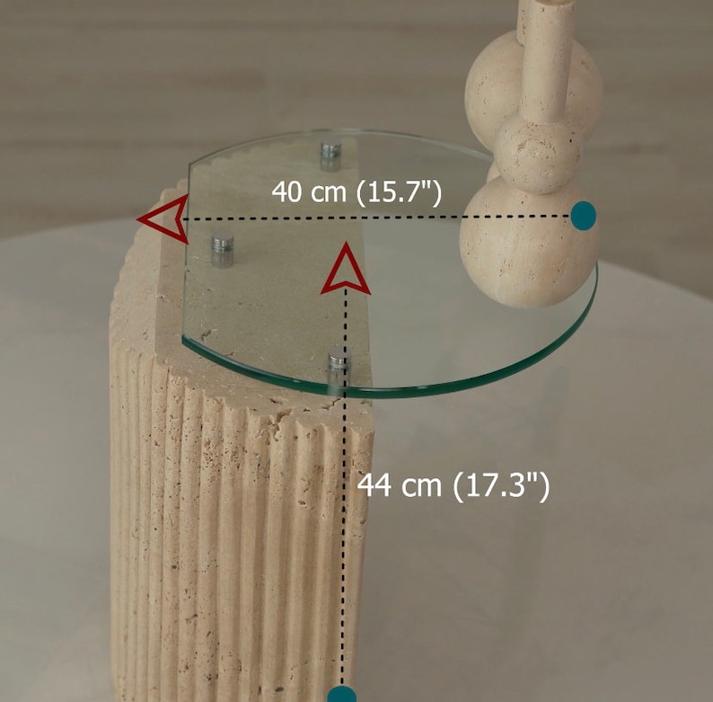 May include: A beige stone side table with a glass top. The table is 44 cm (17.3") tall and the top is 40 cm (15.7") wide.