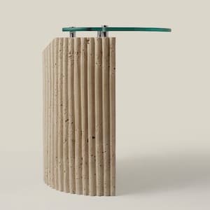 May include: A curved, beige travertine side table with a glass top. The table has a fluted design and a modern style.