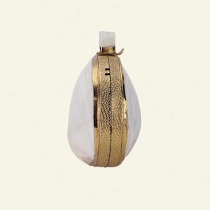 May include: A white, teardrop-shaped clutch bag with a gold-coloured frame and accents. The frame has a textured pattern and a clasp at the top. The bag has a small, rectangular top piece.