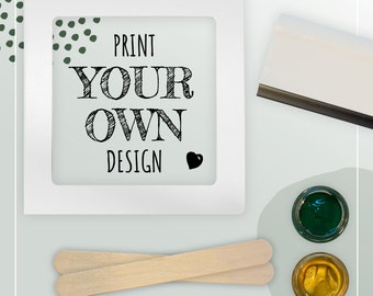 Può includere: Cornice bianca con il testo "Print Your Own Design" all'interno. Sono anche mostrati due bastoncini di legno, un barattolo di vernice verde e un barattolo di vernice dorata.