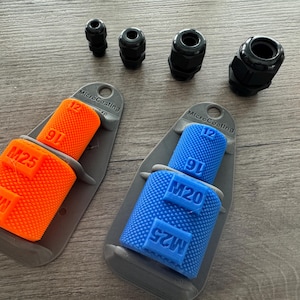 Può includere: Un assortimento di pressacavi neri e protezioni per pressacavi MicroCoating arancioni e blu. Le protezioni sono etichettate con dimensioni come M20, M25, 12 e 91. Gli articoli sono disposti su una superficie di legno.
