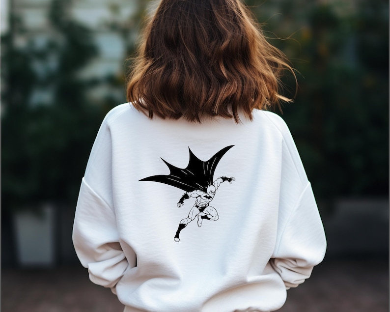K&ouml;nnte beinhalten: Wei&szlig;er Pullover mit einem schwarz-wei&szlig;en Grafikdruck von Batman im Flug.