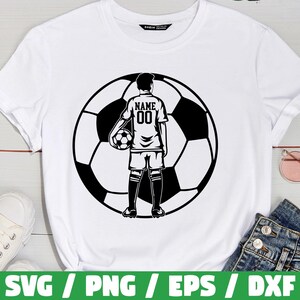 Peut inclure: T-shirt blanc avec un graphisme noir et blanc d'un joueur de football tenant un ballon de football devant un ballon de football. Le maillot du joueur porte le mot "NAME" et le num&eacute;ro "00" au dos. Le t-shirt est pr&eacute;sent&eacute; sur une surface blanche.