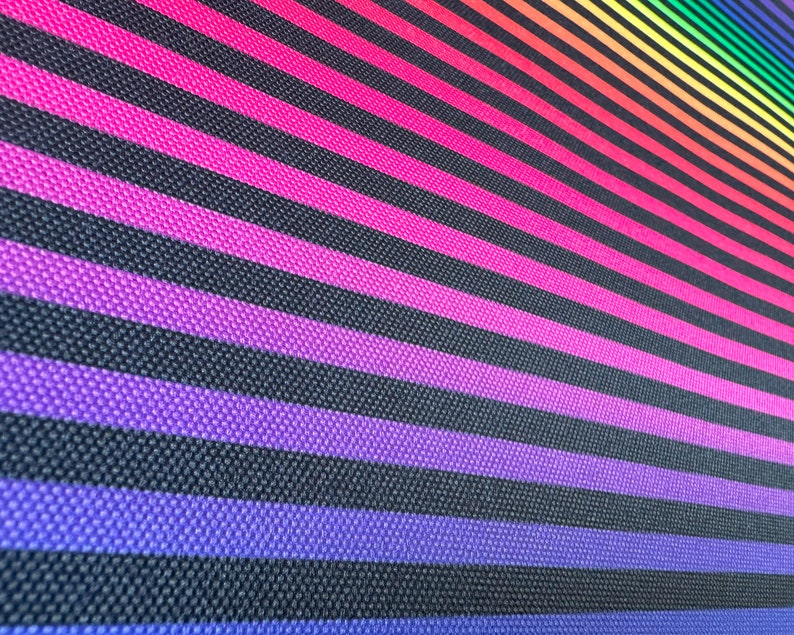 May include: A close-up of a black fabric with diagonal stripes of various colors, including pink, purple, blue, green, yellow, orange, and red. The stripes are arranged in a gradient pattern, creating a rainbow effect.