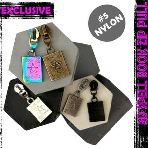 Könnte beinhalten: Vier Reißverschluss-Zipper mit einem Buch der Zauber-Design. Die Zipper sind aus Metall und haben eine Vielzahl von Oberflächen, darunter Silber, Gold und schillernd. Die Reißverschluss-Zipper sind mit dem Text "Book of Spells" beschriftet.