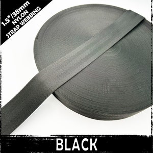 Könnte beinhalten: Schwarzes Nylon-Gurtband, 1,5 Zoll breit, oder 38 mm. Das Band ist aufgerollt und zeigt die Textur des Materials.