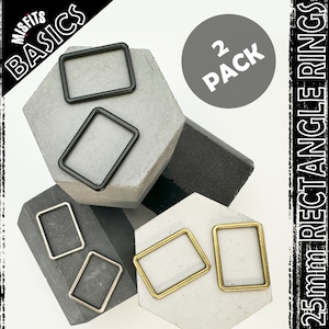 Könnte beinhalten: Zwei Packungen mit 25 mm großen rechteckigen Ringen in Schwarz und Gold. Die Ringe liegen auf einer grauen, strukturierten Oberfläche. Der Text "2 PACK" ist auf dem Bild zu sehen.