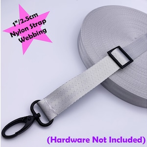 Könnte beinhalten: Eine Rolle graues Nylon-Gurtband mit einer Breite von 2,5 cm. Das Band ist mit einer schwarzen Kunststoffschnalle und einem schwarzen Metall-Drehhaken dargestellt. Die Beschläge sind nicht im Lieferumfang enthalten.