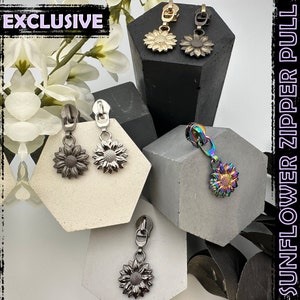 May include: Four different sunflower zipper pulls. The pulls are silver, black, rainbow, and gold. The word "EXCLUSIVE" is in the top left corner of the image.