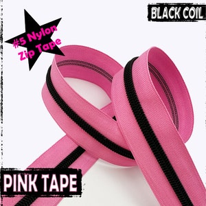 Puede incluir: Primer plano de una cinta de cremallera de nylon rosa con una cremallera de espiral negra. La cinta está etiquetada con "#5 Nylon Zip Tape" y "PINK TAPE".