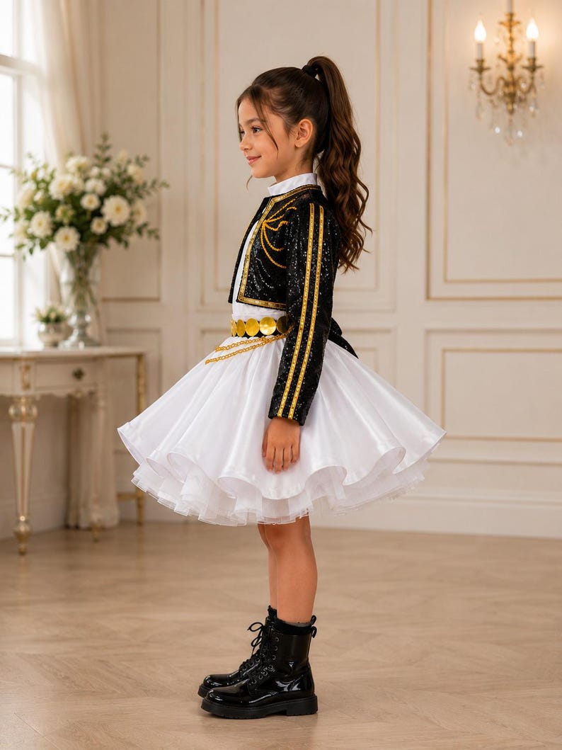 May include: A black sequined bolero jacket with gold trim worn over a white dress with a full, layered skirt. The outfit features a gold coin belt with a chain detail at the waist and is paired with black lace-up boots, creating a structured look.