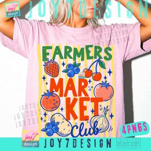 May include: Pink t-shirt with a colorful graphic design. The design features the words "FARMERS MARKET CLUB" with illustrations of fruits and vegetables, including a strawberry, blueberries, cherries, tomato, potato, and onion. The shirt has a crew neck.