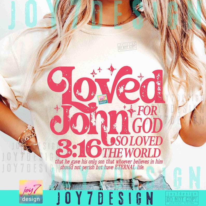Op de afbeelding: Cr&egrave;mekleurig T-shirt met de tekst "Loved for John 3:16" in een vetgedrukte, roze lettertype. Het ontwerp bevat sterren en de zin "So loved the world" in een gestileerd schrift. Het shirt bevat ook een bijbelvers.
