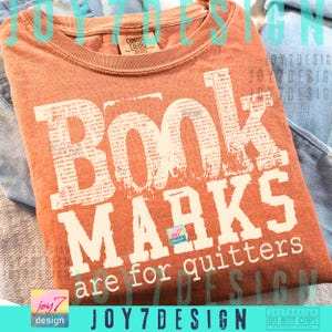 May include: An orange Comfort Colors t-shirt with the text "Book Marks are for quitters" in a distressed white font. The shirt is folded and appears to be made of soft material. The design includes the Joy7Design logo.