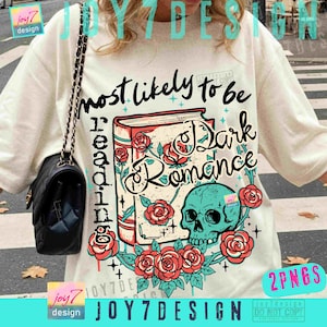 May include: Cream-colored t-shirt featuring a graphic design with the text "most likely to be reading Dark Romance." The design includes a book, roses, and a teal skull. A black purse with a chain strap hangs on the left.