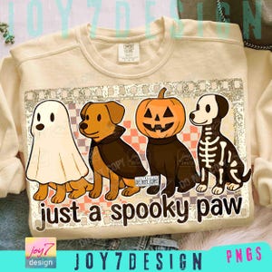 以下が含まれることがあります： ハロウィーンをテーマにしたグラフィックが特徴のクリーム色のスウェットシャツ。デザインには、幽霊、吸血鬼、カボチャ、スケルトンに扮した4匹の漫画の犬が描かれています。「just a spooky paw」というテキストが犬の下にあります。