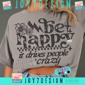 May include: Gray t-shirt with the words "bet happy it drives people crazy" in a black, bold font. The shirt features a floral design and a checkered pattern. The shirt is a relaxed fit.