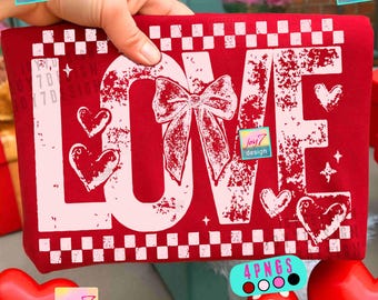 May include: A red fabric item with the word "LOVE" in large, distressed white letters. A white bow and hearts are featured in the design. The item is held by a hand and includes the text "joy7 design".