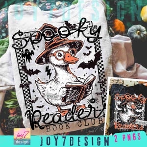 May include: White t-shirt with a Halloween graphic. The design shows a duck in a witch's hat and glasses, reading a book. The text reads "Spooky Reader Book Club" with bats and a spider web.