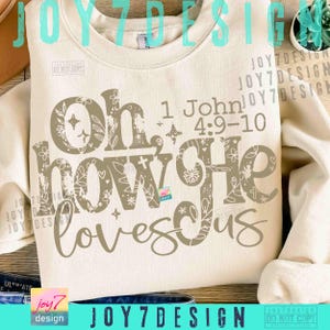 May include: Cream-colored sweatshirt with the text "Oh, how He loves us" in a decorative font. The text includes the Bible verse 1 John 4:9-10. The design features floral and star accents.