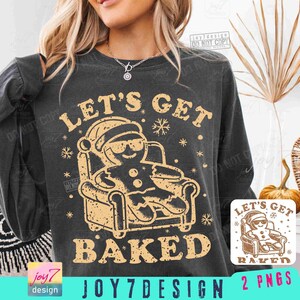 Puede incluir: Sudadera gris oscuro con un gráfico de un hombre de jengibre con gafas de sol relajándose en una silla. El texto "LET'S GET BAKED" está arriba y abajo del gráfico. El texto adicional incluye "JOY7DESIGN" y "2 PNGS".