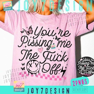 May include: Pink t-shirt with the phrase "You're Pissing me The Fuck Off" in black script. The design includes butterflies, a heart, stars, a smiley face, and a checkered pattern. The shirt has a crew neck.