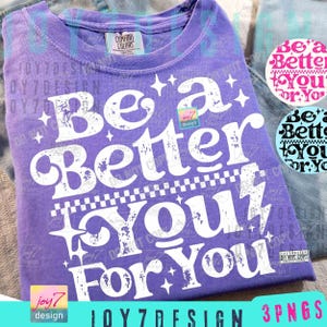 May include: A purple Comfort Colors t-shirt with the phrase "Be a Better You For You" in distressed white lettering. The design includes stars and a checkered pattern. Additional graphics are visible.