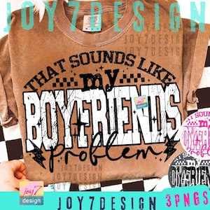 May include: A brown Comfort Colors t-shirt with the text "THAT SOUNDS LIKE my BOYFRIENDS problem" in a distressed white font. The design includes lightning bolts and stars. The shirt has a crew neck and short sleeves.