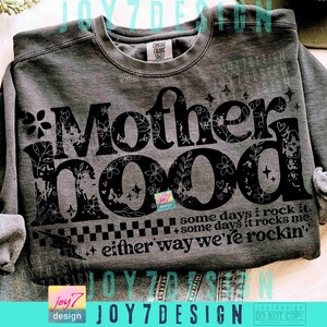 Peut inclure: Un sweat-shirt gris avec le mot "Motherhood" en grandes lettres noires d&eacute;cor&eacute;es de motifs floraux. Le texte "some days I rock it, some days it rocks me, either way we're rockin'" est imprim&eacute; en dessous. Le sweat-shirt a une &eacute;tiquette Comfort Colors.
