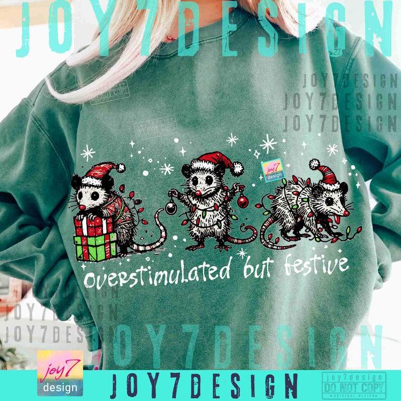 Puede incluir: Sudadera verde azulado con tres zarig&uuml;eyas con gorros de Pap&aacute; Noel y luces navide&ntilde;as. El texto "overstimulated but festive" est&aacute; debajo, con copos de nieve decorativos.