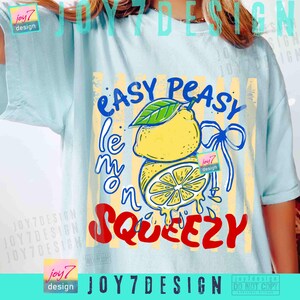Peut inclure: T-shirt bleu clair avec un motif de citron. Le motif comprend un citron entier avec une feuille verte, un citron tranch&eacute; et les mots "Easy Peasy Lemon Squeezy" en bleu et rouge. Des rayures verticales jaunes sont derri&egrave;re le citron.