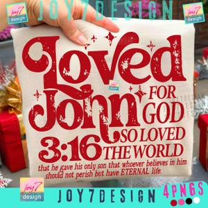Op de afbeelding: Een cr&egrave;mekleurig t-shirt met de rode woorden "Loved For John 3:16", samen met de zin "So loved the world" en een bijbelvers. Het ontwerp bevat steraccenten en de tekst "that he gave his only son that whoever believes in him should not perish but have ETERNAL life."