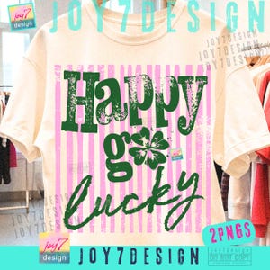 Może przedstawiać: Kremowa koszulka z zielonym napisem "Happy g Lucky" i grafiką czterolistnej koniczyny. Projekt umieszczono na r&oacute;żowo-białym paskowanym tle. Koszulka ma kr&oacute;tkie rękawy i okrągły dekolt.