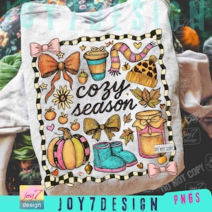 Könnte beinhalten: Weißes Sweatshirt mit einem farbenfrohen "cozy season" -Motiv. Das Design umfasst einen Kürbis, Schleifen, Stiefel, eine Kaffeetasse, einen Schal, eine Mütze, Blätter und ein Glas Honig. Die Grafik ist mit einem schwarz-weißen Schachbrettmuster umrandet.