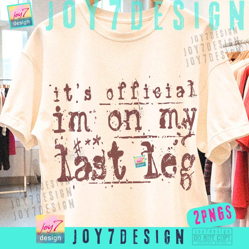 May include: A cream-colored t-shirt with the phrase "it's official I'm on my last leg" printed in brown. The design has a distressed, vintage look. The shirt is hanging on a wooden hanger.