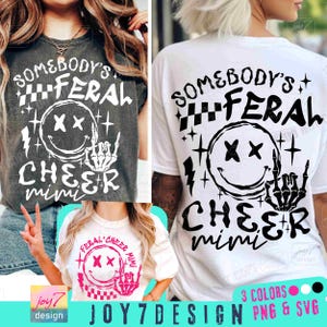 Puede incluir: Una camiseta blanca con texto negro que dice "Somebody's Feral Cheer Mimi" con una cara sonriente en blanco y negro con una mano de esqueleto. El texto está en una fuente en negrita y de bloque. La camiseta se muestra en una modelo que lleva la camiseta y una modelo que sostiene la camiseta.