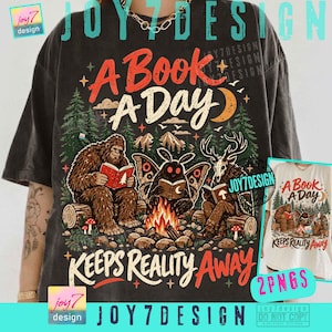 Può includere: Una t-shirt grigio antracite con la grafica di un Bigfoot, una creatura falena e una figura con testa di cervo che leggono libri attorno a un falò in un bosco. Il testo recita A BOOK A DAY KEEPS REALITY AWAY, circondato da stelle e alberi.