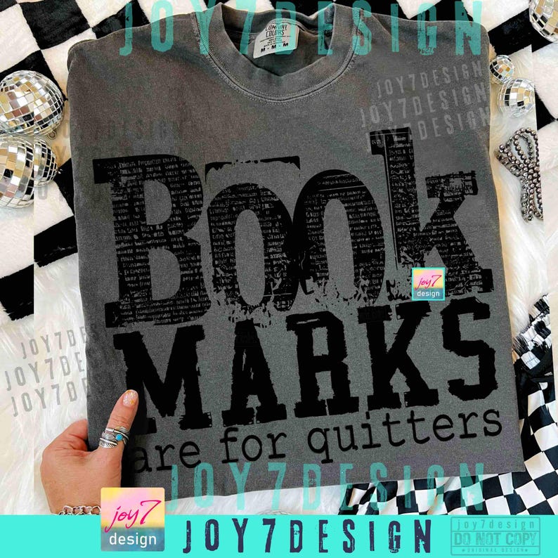 May include: A gray t-shirt with the words "BOOK MARKS are for quitters" in black. The word "BOOK" is large and stylized. The shirt has a crew neck and short sleeves. The shirt is a medium size.