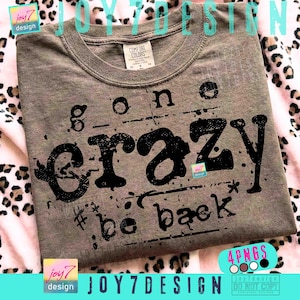 Op de afbeelding: Een grijs Comfort Colors T-shirt met de tekst "gone crazy # be back" in een verweerde zwarte letter. Het shirt heeft een ronde hals en korte mouwen. Het ontwerp bevat een kleine ster en de tekst "joy7 design".