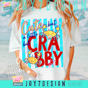 May include: White t-shirt with a colorful graphic design. The design features the text "Cute but a little bit Crabby" in various fonts and colors, along with two yellow crab illustrations. The shirt has a relaxed fit.