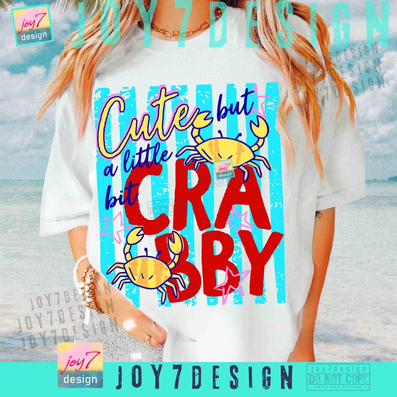 May include: White t-shirt with a colorful graphic design. The design features the text "Cute but a little bit Crabby" in various fonts and colors, along with two yellow crab illustrations. The shirt has a relaxed fit.